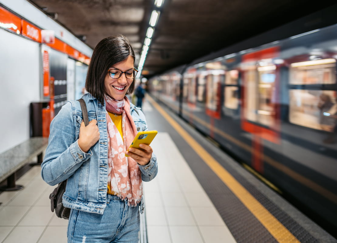 Woman waiting at subway holding her phone.